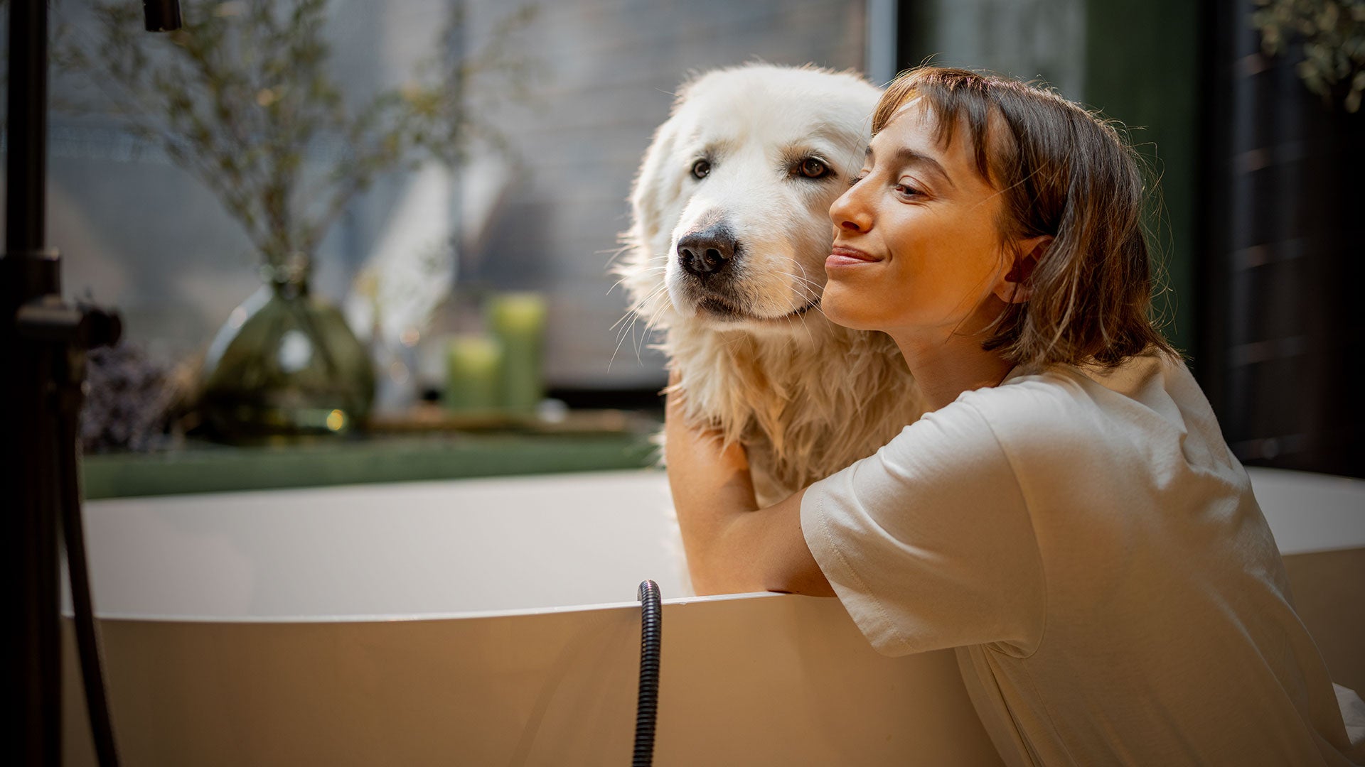 A girl is hugging a dog in the bathtub
